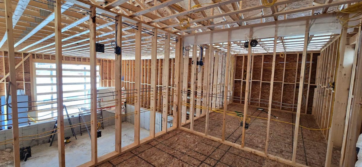 A garage roughed in with wiring run overhead and boxes set for lighting and receptacles.