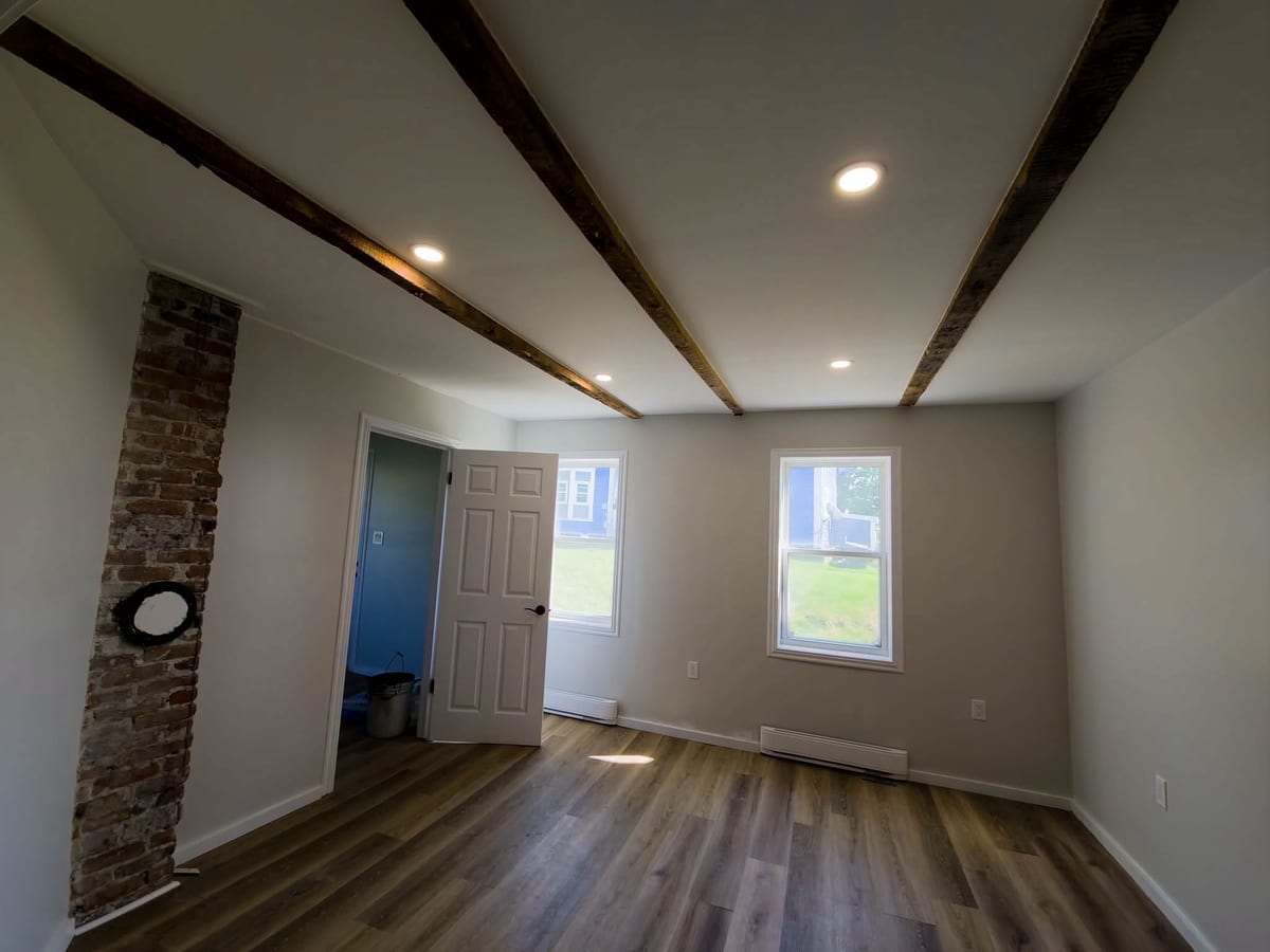 A living room with exposed beams and recessed lighting set between them.