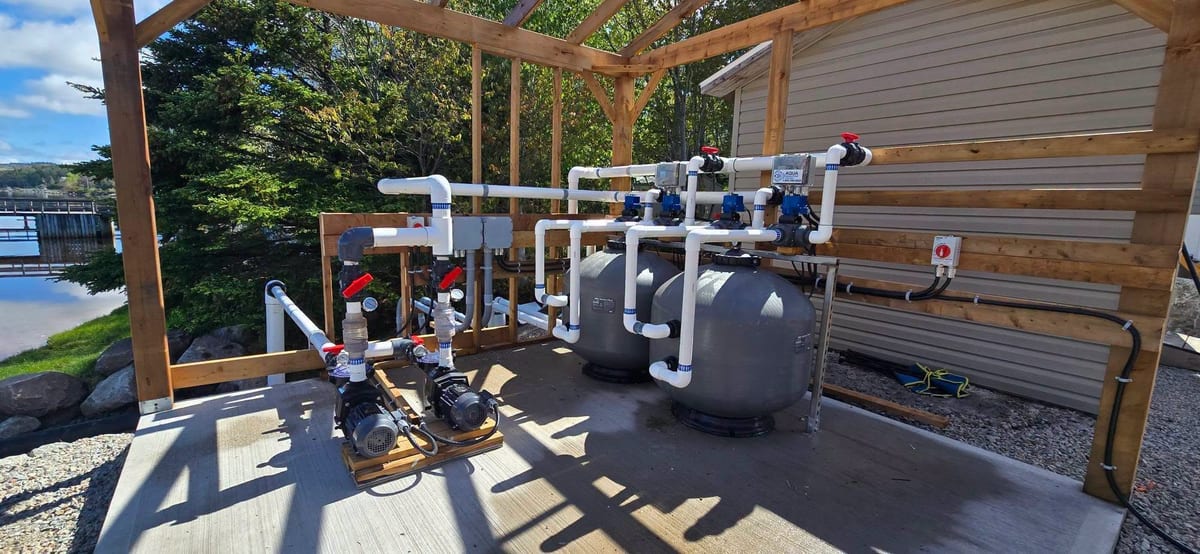 Outdoor pool filtration and pump equipment wired and piped under a covered structure.